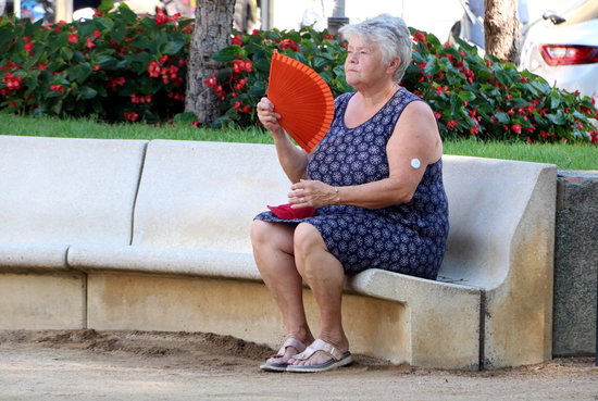 A woman sits on a bench during a hot day