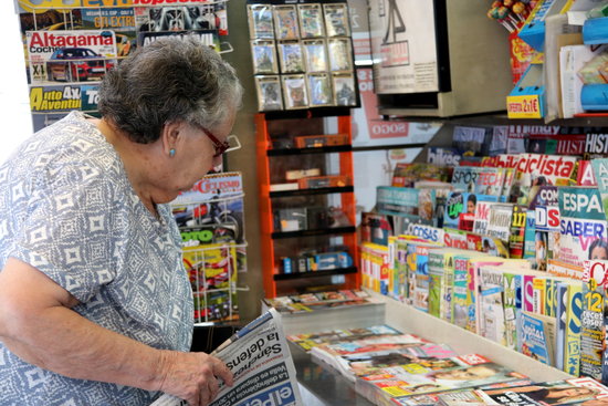 A woman buying a newspaper in a kiosk in Barcelona. 