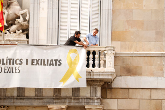 Two workers removing a sign in solidarity with the pro-independence leaders from the government headquarters in 2019