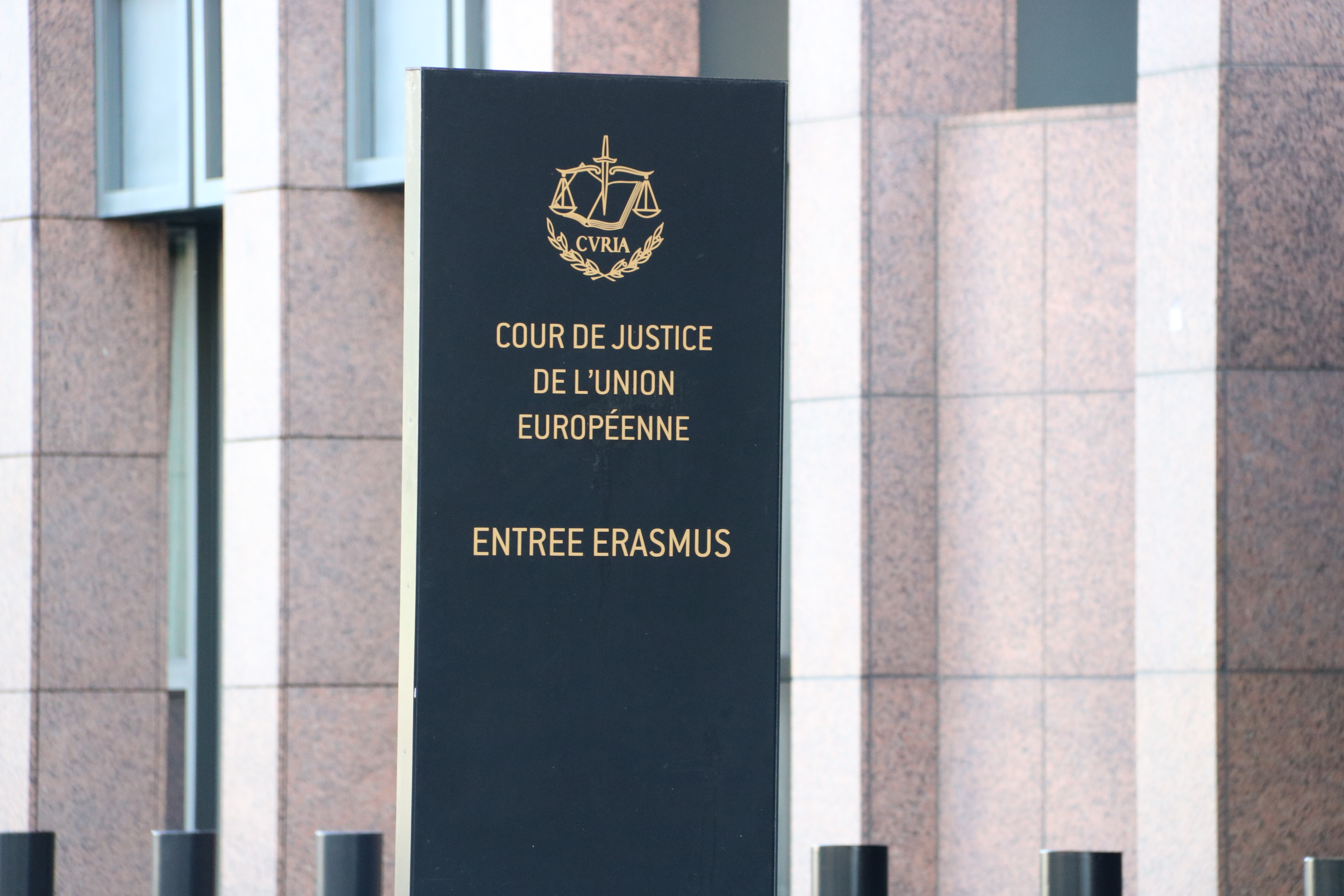 A poster reads 'Cour de Justice de l'Union Européenne' in front of the Court of Justice of the European Union