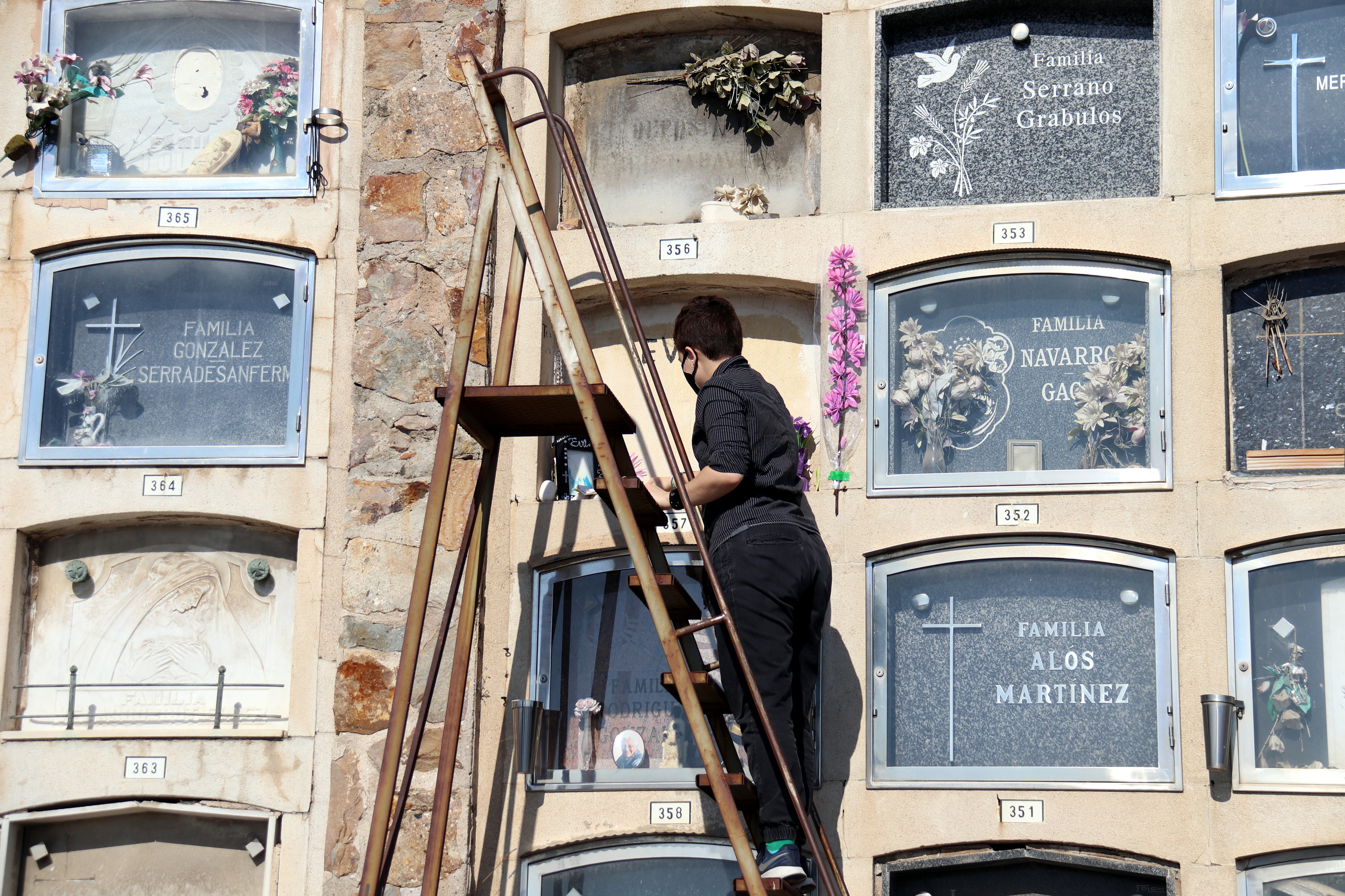 A woman arranging flowers in a grave at the Montjuïc cemetery.