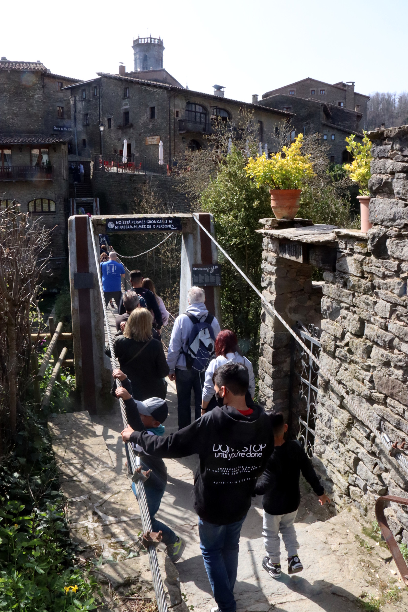 Several people queue to cross Rupit's hanging bridge on April 3, 2021