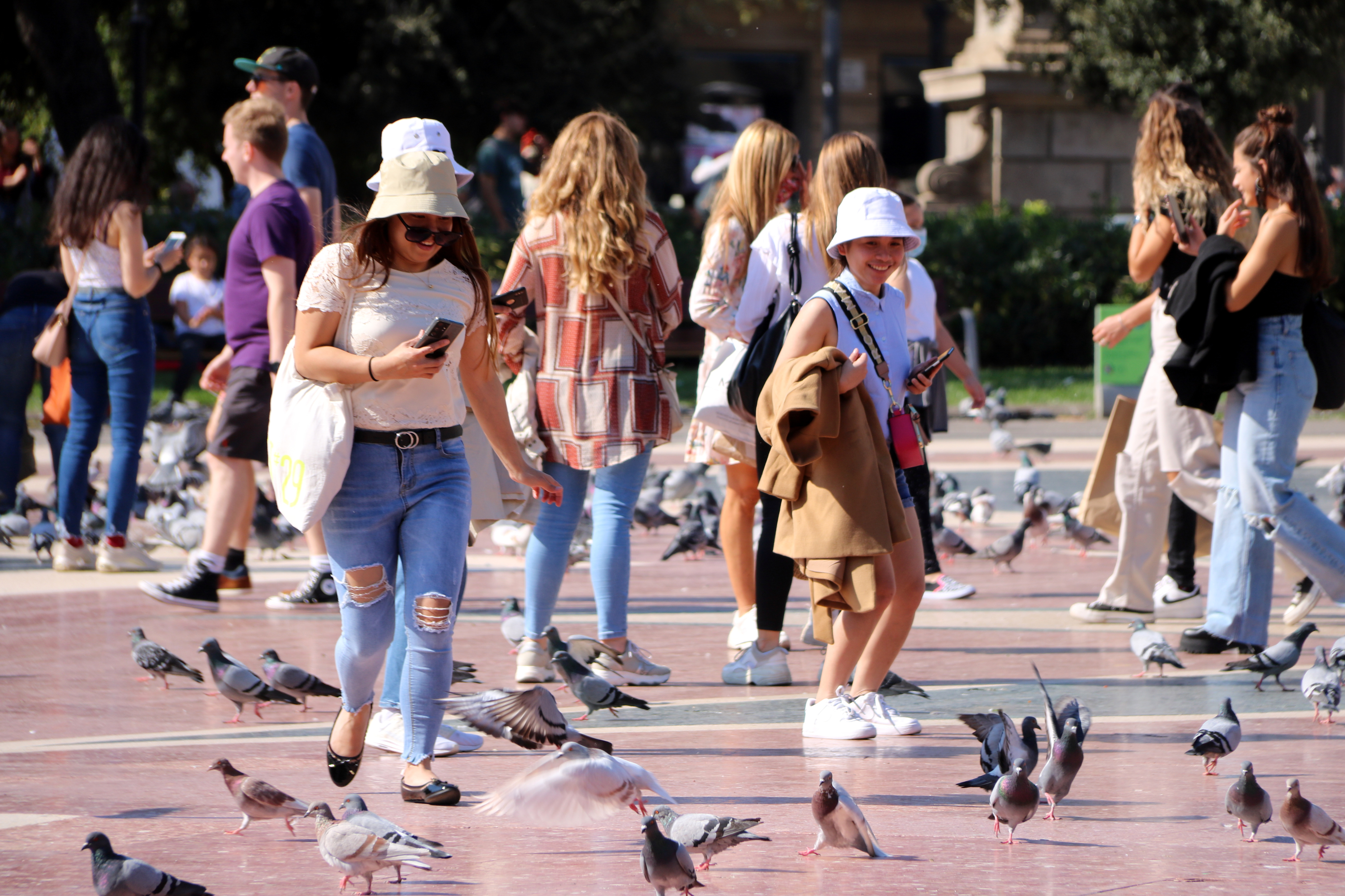 Tourists taking pictures of pigeons at Plaça de Catalunya, Barcelona