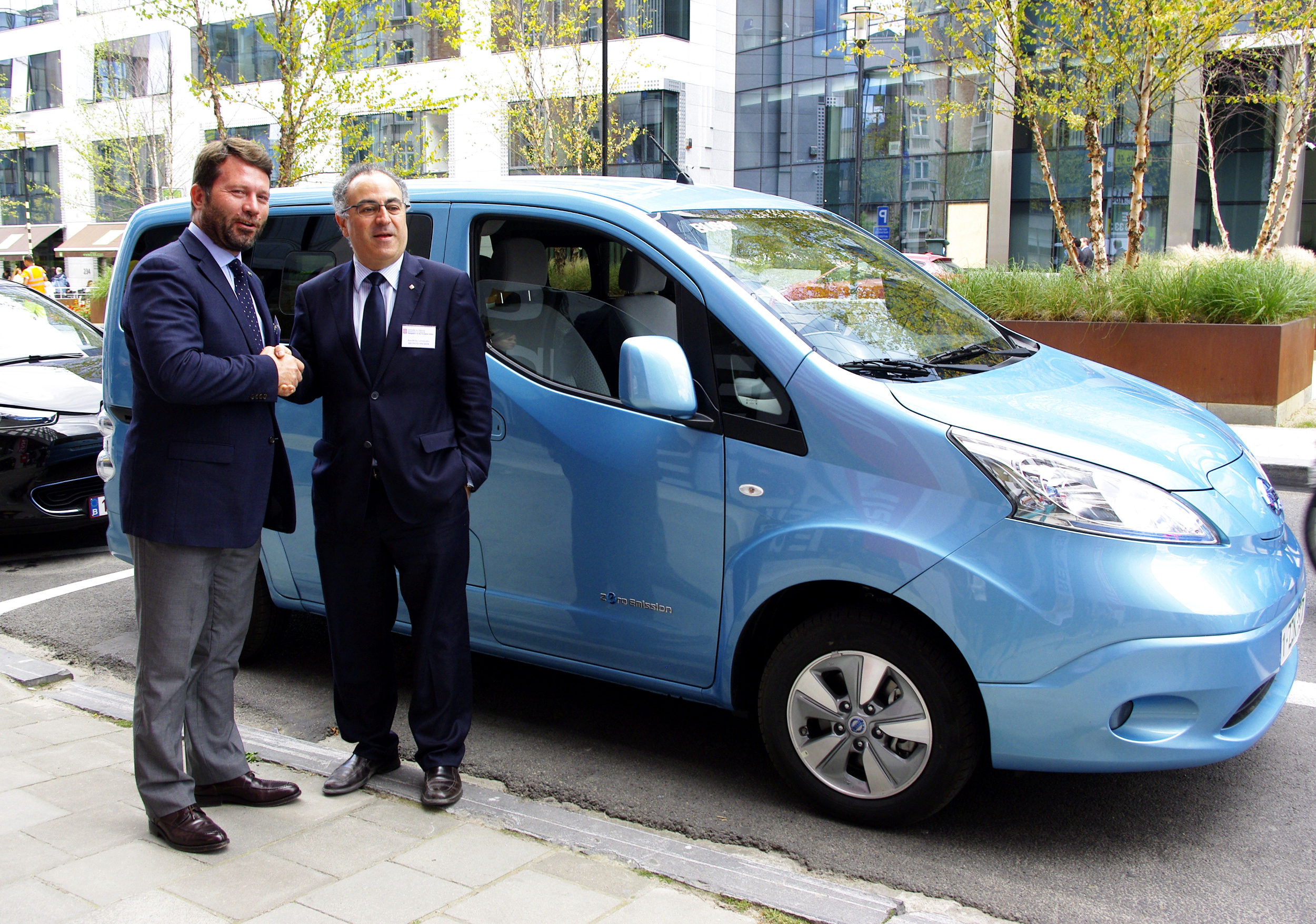 The Communications Director of Nissan Iberia,  Francesc Corberó, and the Catalan Delegate to the EU, Pere Puig, shake hands in front of an electric van (by ACN)