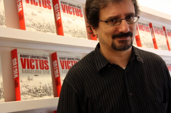 Albert Sánchez Piñol posing in front of a few copies of 'Victus' in 2013 (by ACN)