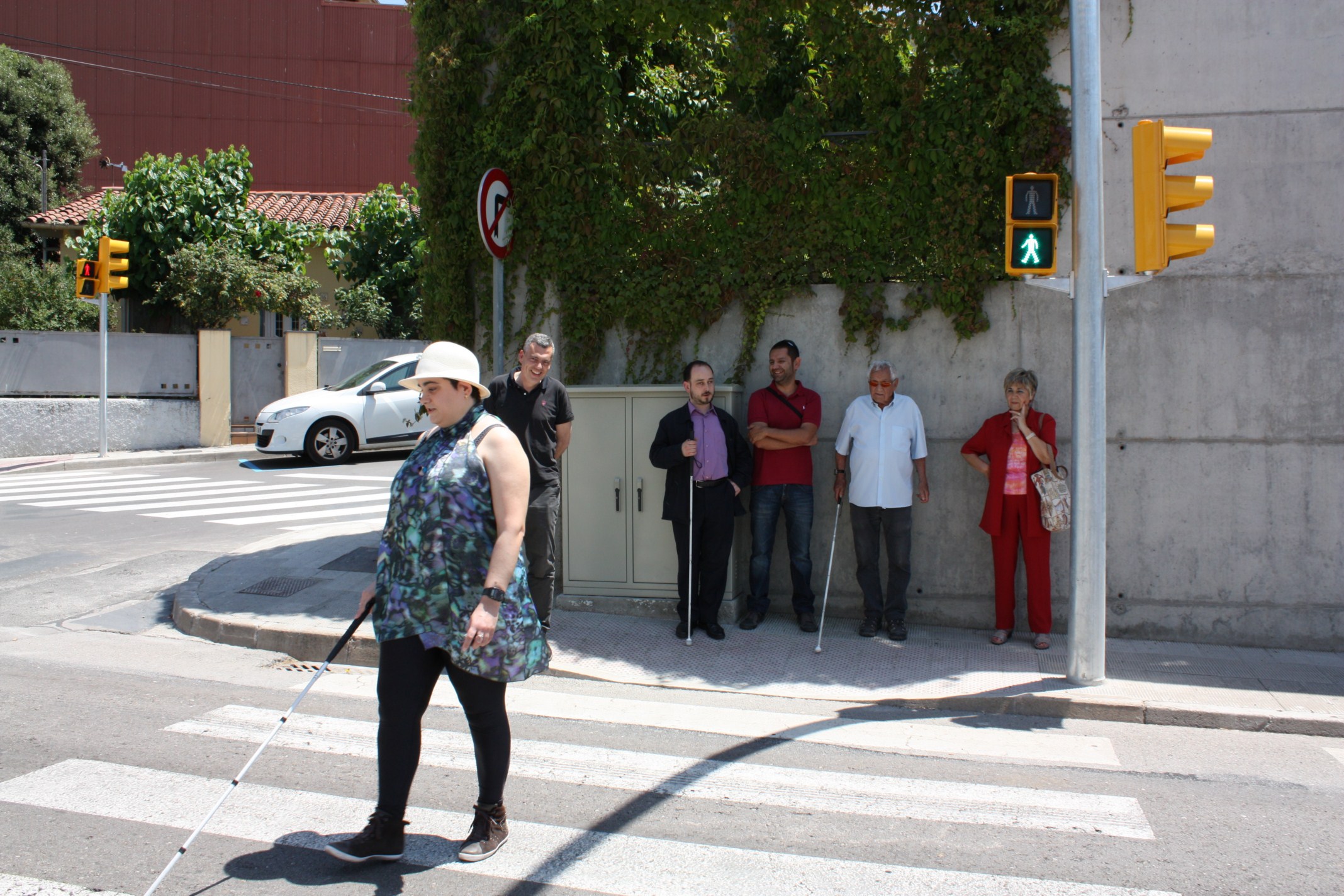 Blind woman crossing a pedestrian crossing regulated by an adapted traffic light (by ACN) 