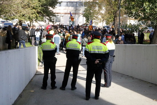 Four agents of the Mossos d'Esquadra at the entrance of Berga's Court. In front of  them a demonstration in support of Montse Venturós (by ACN)