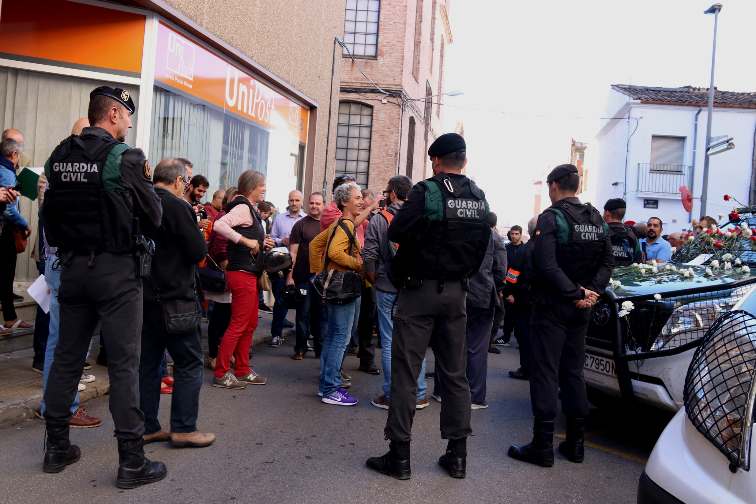 Guardia Civil officers guard delivery company Unipost office while raiding it; citizens protest