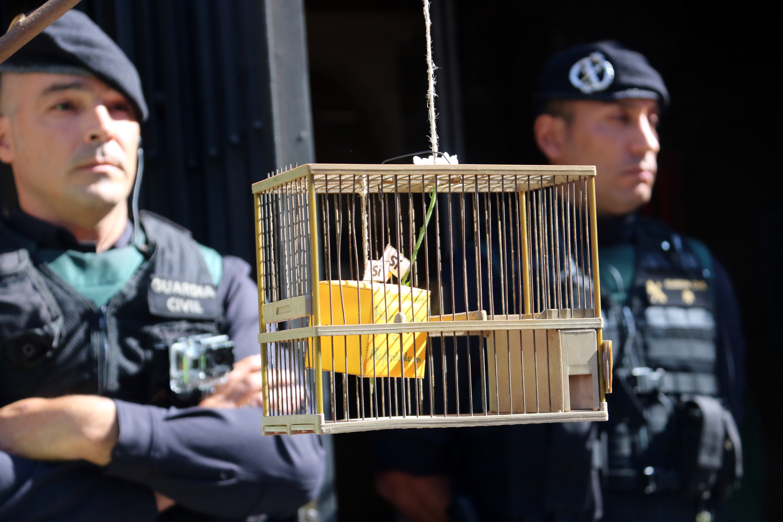Two Spain's Guardia Civil officers in a demonstration with a symbolic ballot box inside a cage