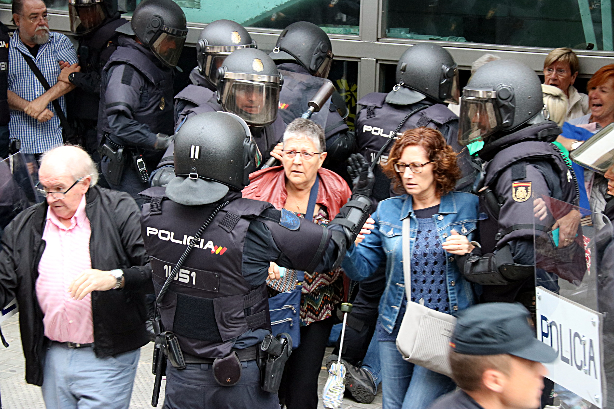 Spanish police officers circle two women outside a polling station on October 1 (by ACN)