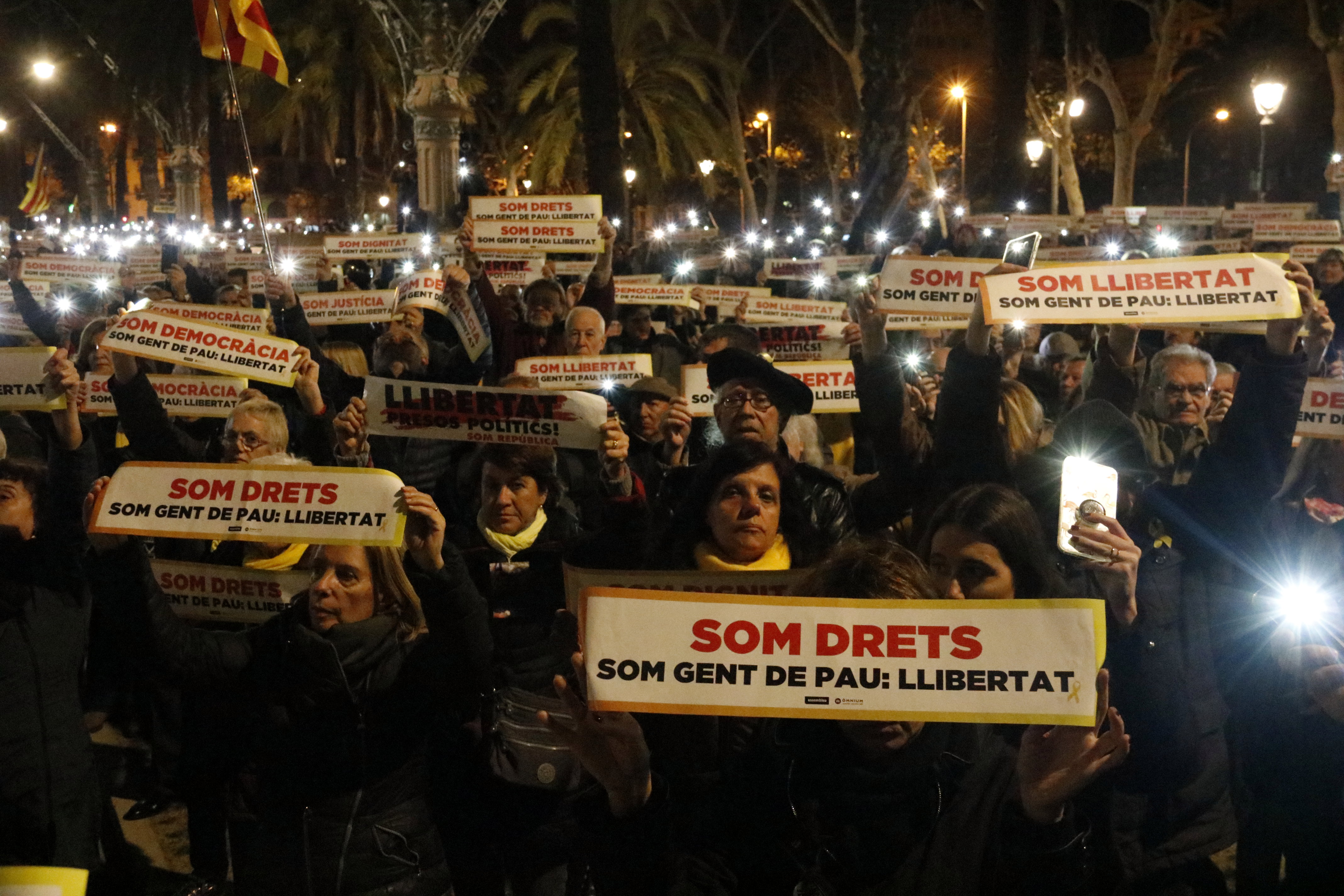 Participants in the demonstration to demand freedom for Jordi Sànchez and Jordi Cuixart hold a sign reading 'We are Rights' and 'We are people of peace: freedom' with their mobile flashlights lit in Barcelona on January 16, 2018 (by Laura Fíguls)