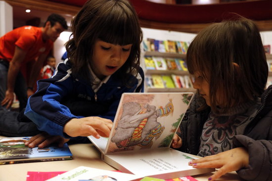 Two children look at a book during thr 34th Children's Book Fair in Mollerussa on April 11 2018 (by Oriol Bosch)