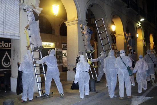 A group in white protective clothes removing yellow signs in La Bisbal d'Empordà on August 29, 2018 (by Marina López)