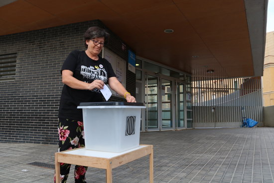 A woman symbolically casting a ballot in front of a school that was used as a polling station in the Catalan referendum (by Elisenda Rosanas)