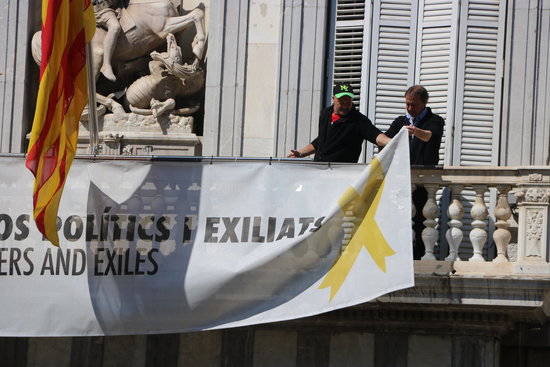 Two workers remove the banners on the balcony of the government HQ, March 22, 2019. (Photo: Miquel Codolar)