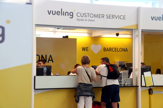 Passengers visit the Vueling customer service desk in the Barcelona airport (by Miquel Codolar)