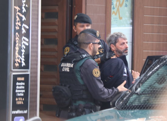 Spanish police officers escort one of the pro-independence activists arrested on Monday out of his house (by Miquel Codolar)