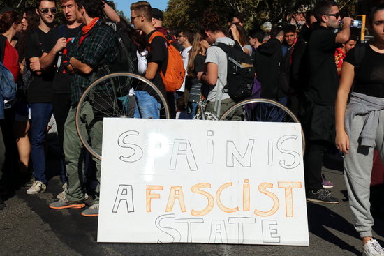 Protesters with a sign reading “Spain is a fascist state” in Barcelona (by Lluís Sibils)