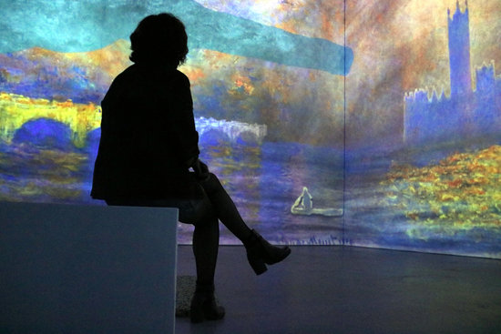 A woman sits in front of one of the immersive Monet exhibitions at the Ideal arts center in Poblenou, Barcelona (by Pilar Tomás)