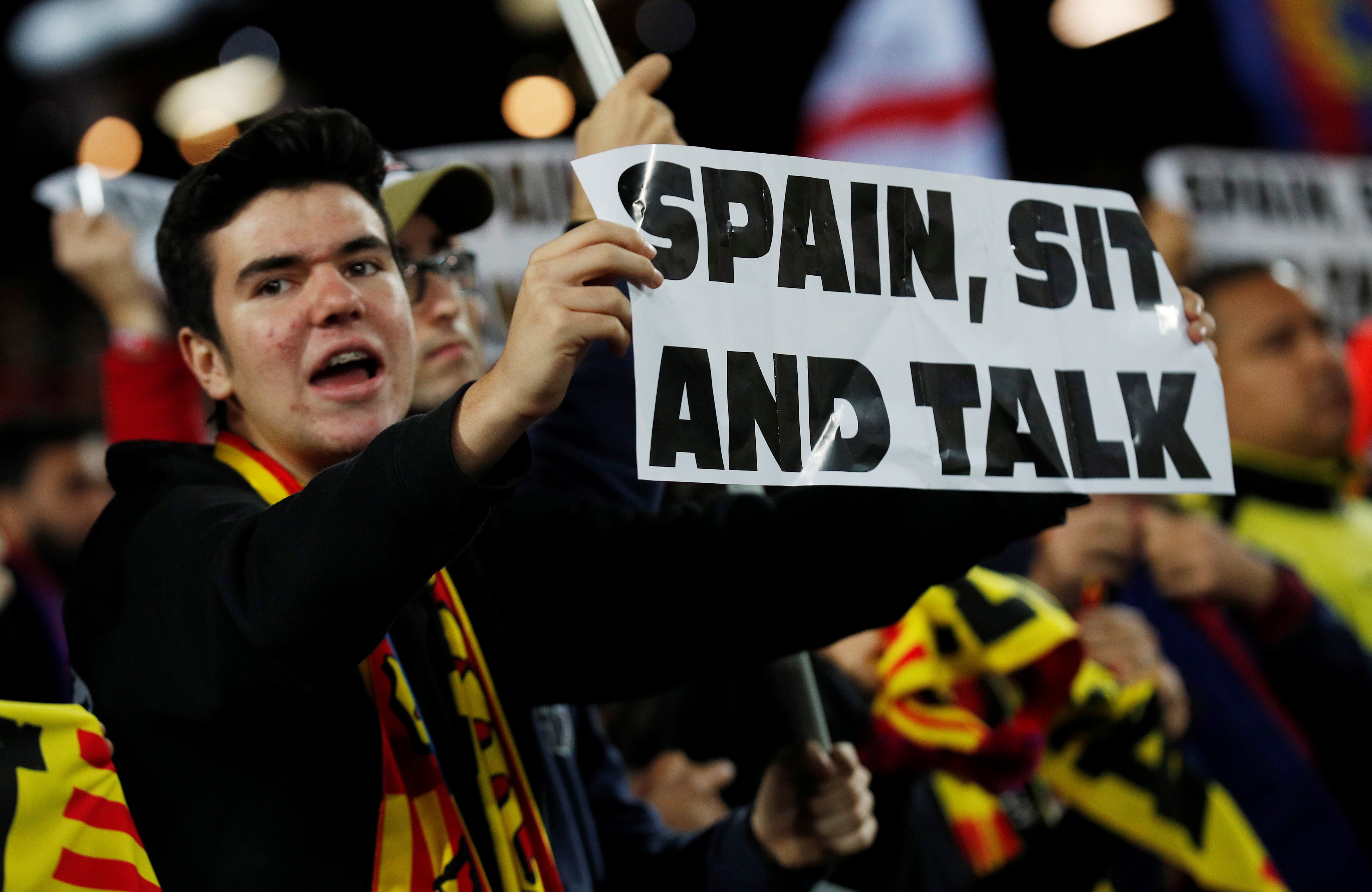 A Barcelona fan holds a sign reading “Spain, Sit And Talk” at the Champions League clash between FC Barcelona and Slavia Prague (by REUTERS/Albert Gea)