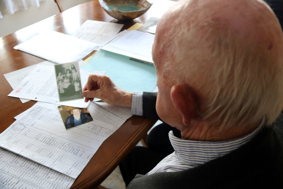 Josep Sabatés looking at a photograph of his father and his siblings, one of the few records he has of his uncle (by Estefania Escolà)