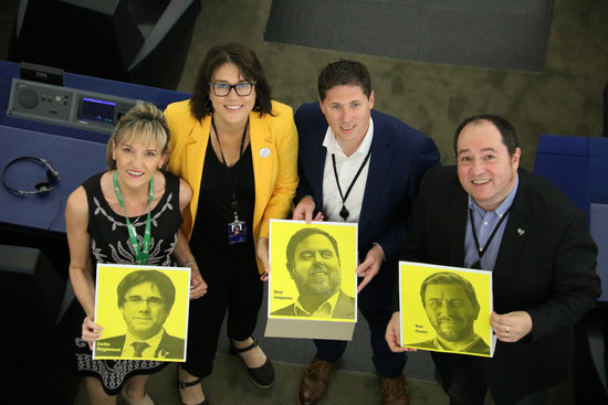 MEPs Martina Anderson, Matt Carthy, Diana Riba, and Pernando Barrena hold up photos of Carles Puigdemont, Oriol Junqueras, and Toni Comín in the European Parliament plenary session on Jul 2, 2019 (by Natàlia Segura)