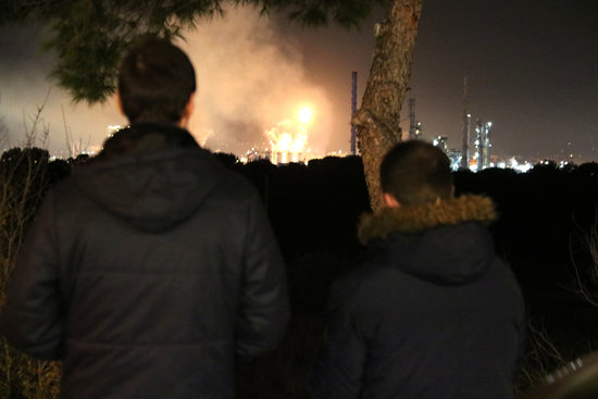 Two people watch flames in the aftermath of the explosion in the chemical plant in Tarragona on January 14, 2020 (by Núria Torres)
