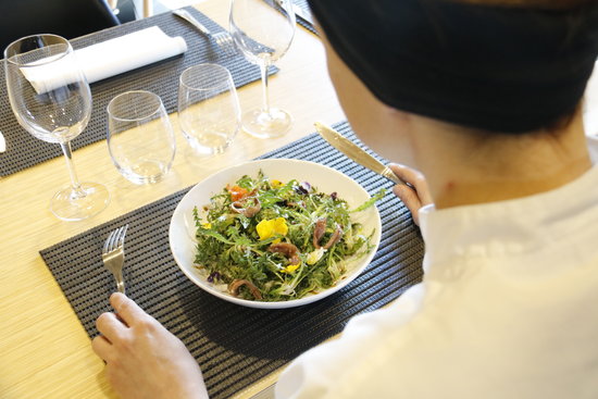 A customer in a restaurant about to eat a chicory salad (by Ferran Queralt) 