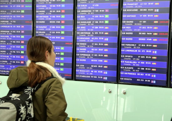 A passenger looks at the flight information screens in Barcelona airport, after a spate of flights were cancelled on the first day of the state of alarm declared for the covid-19 coronavirus crisis (by Àlex Recolons)
