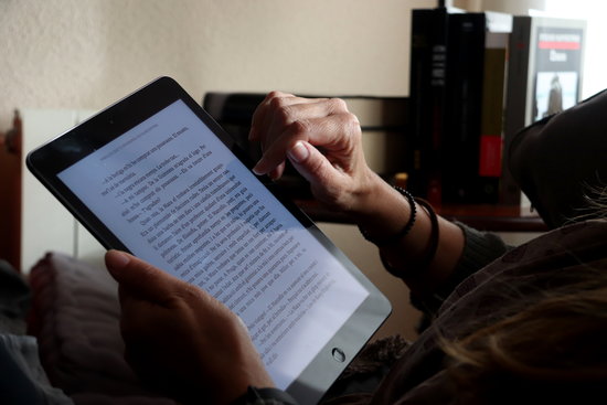 A person reads an e-book at home (by Mar Vila)