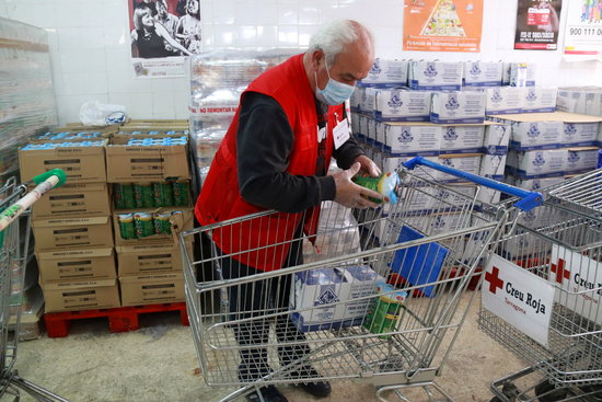 A volunteer for the Red Cross in Tarragona fills up a shopping cart for a person in a vulnerable situation (by Eloi Tost)