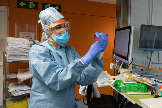 A medic puts on gloves before treating a patient with covid-19, March 23, 2020 (by Francisco Avia/Hospital Clínic de Barcelona)