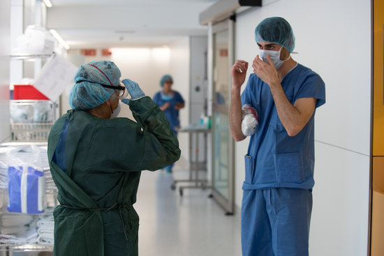 A healthcare professional helps a colleague before treating a patient with covid-19 in Barcelona’s Hospital Clínic, April 6, 2020, (by Francisco Àvia/Hospital Clínic)