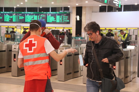 A volunteer of Red Cross distributing masks in Barcelona's main train station, Sants, on April 14, 2020 (by Albert Cadanet)