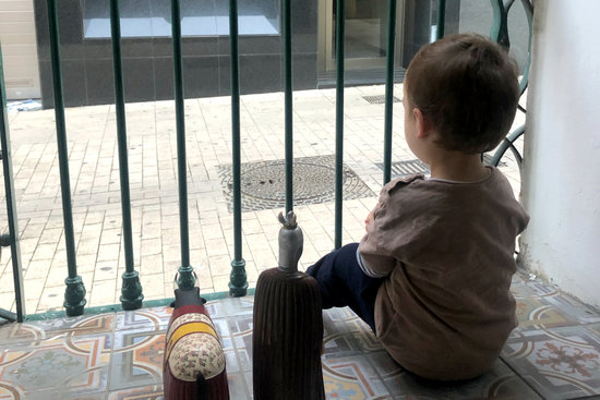 A child looks out at the street from his home during confinement (by Jordi Pujolar)