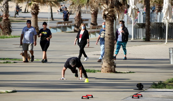 A man exercises as others go for strolles in Badalona on the first day after lockdown restrictions were lifted for the whole population (by Àlex Recolons)