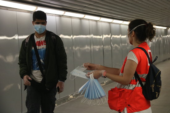A Red Cross volunteer gives out Spanish government masks on Barcelona's underground on May 4, 2020 (by Albert Cadanet)