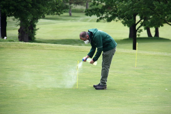 A staff member at the Aravell Golf & Country Club disinfects some of the equipment on the course (by Albert Lijarcio)