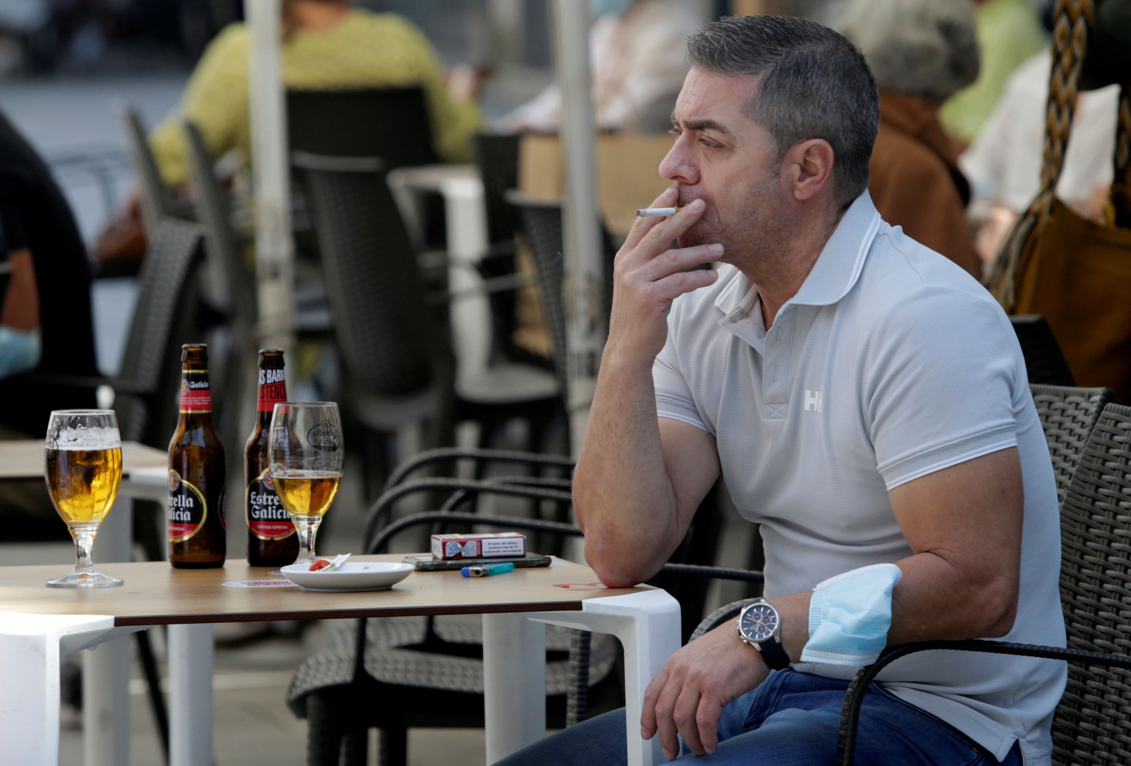 A man sitting on a bar terrace smoking a cigarette (by Miguel Vidal/Reuters)