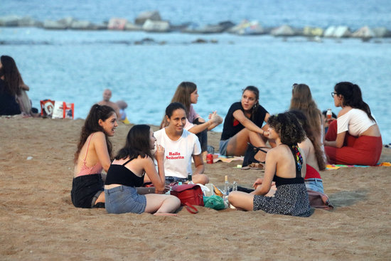 A group of young people enjoy drinks and food on Barcelona beach (by Miquel Codolar)