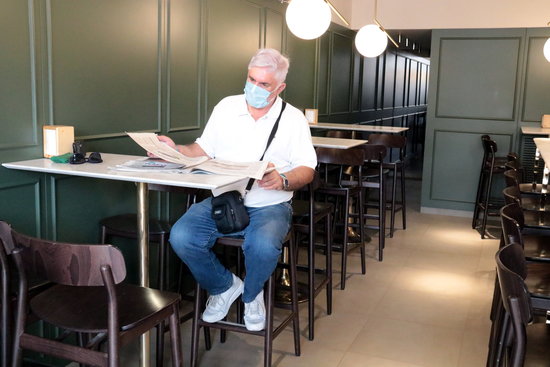 A customer reads a newspaper in a restaurant in Lleida on the first day the interiors were allowed to reopen, August 11, 2020 (by Salvador Miret)