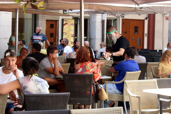 Image of a waiter serving sanitizer to clients in a bar terrace, in Girona, on August 17, 2020 (by Xavier Pi)