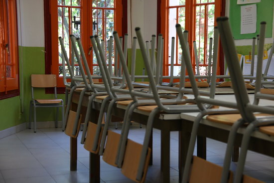 A school classroom with chairs stacked onto the tables (by Elisenda Rosanas)