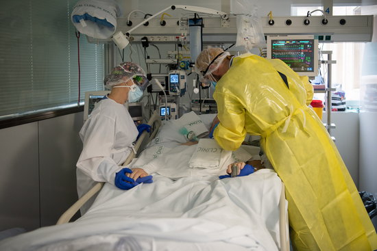 Two health workers visiting a Covid-19 patient in an ICU in Barcelona's Hospital Clínic hospital on October 23, 2020 (by Hospital Clínic)