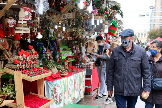 A couple peruse the stalls of the Santa Llúcia Christmas fair in the centre of Barcelona, November 2020 (by Carola López)