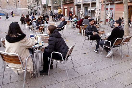 People sit at a bar terrace in a square in Barcelona (by Jordi Bataller)