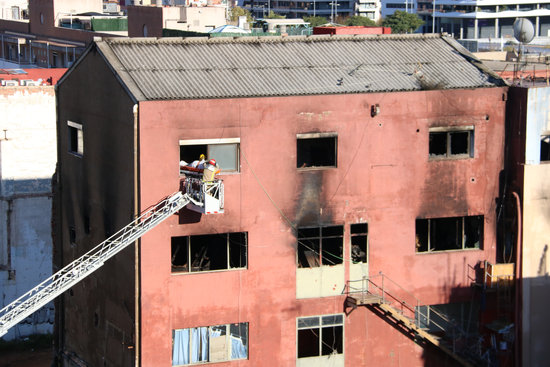 Firefighters bring one of the victims out of the warehouse that caught fire on December 9, 2020 (by Albert Segura Lorrio)