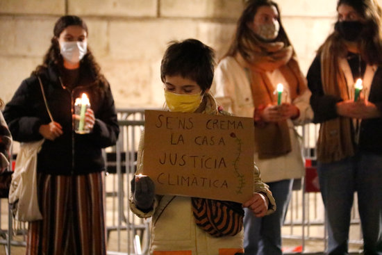 A child holds a placard which reads “Our house is being burnt, climate justice” at a protest on December 11, 2020 (by Blanca Blay)