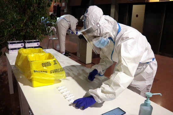 A health worker in full protective equipment deposits a sample collected by an antigen test in Lleida (by Salvador Miret)