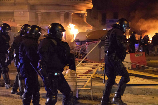 Some police officers facing riots in Barcelona's city center with some dumpsters burning down, on February 17, 2021 (by Blanca Blay)